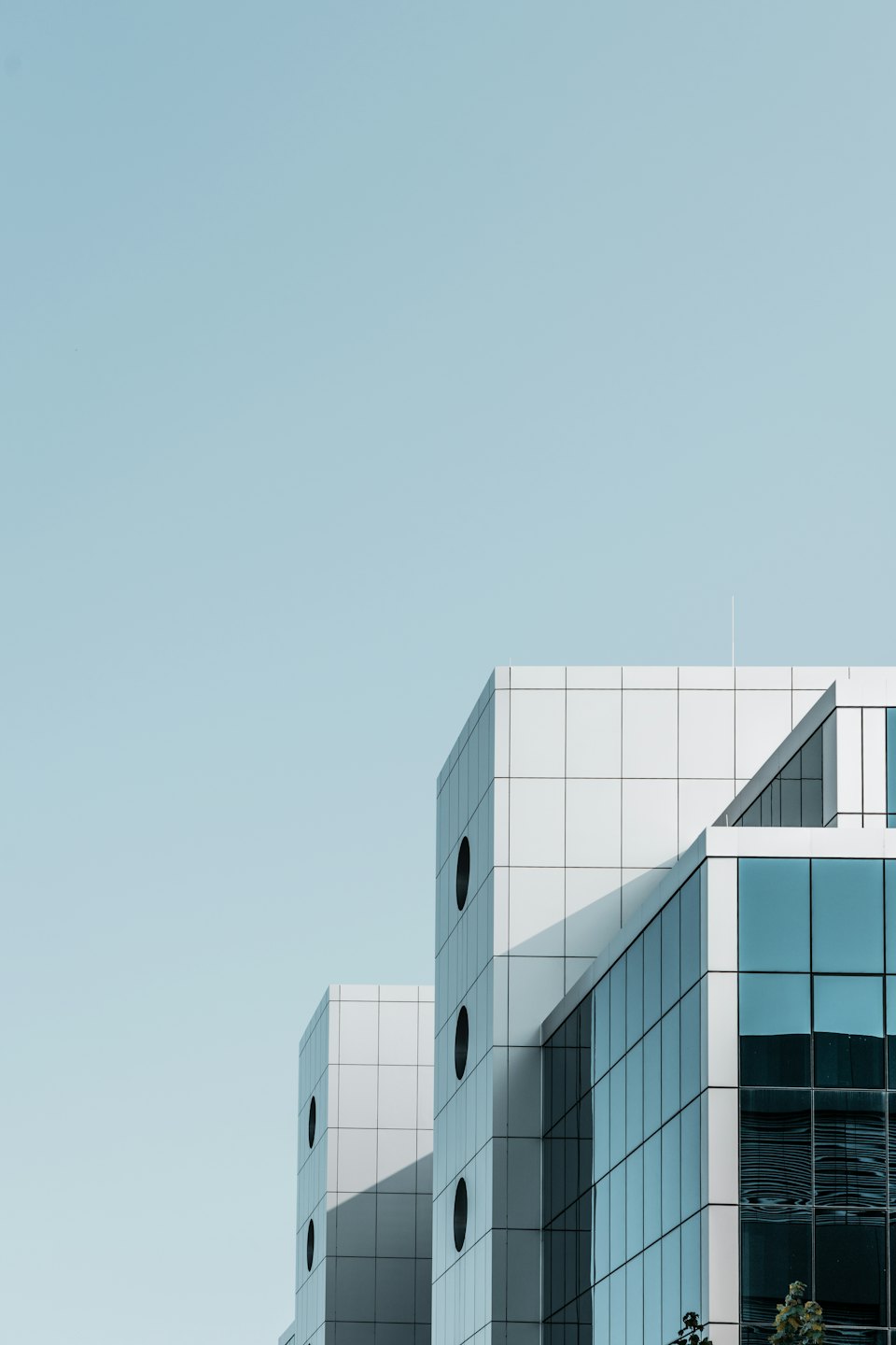 Geometrik beyaz panelleri ve yuvarlak pencereleri olan modern ofis binası.